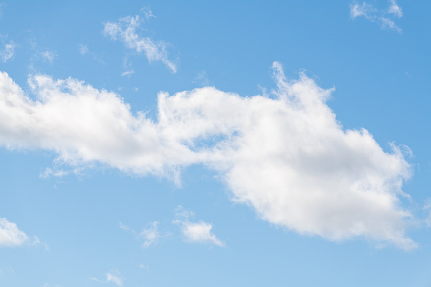 Fluffy White Clouds Against a Clear Blue Sky Background