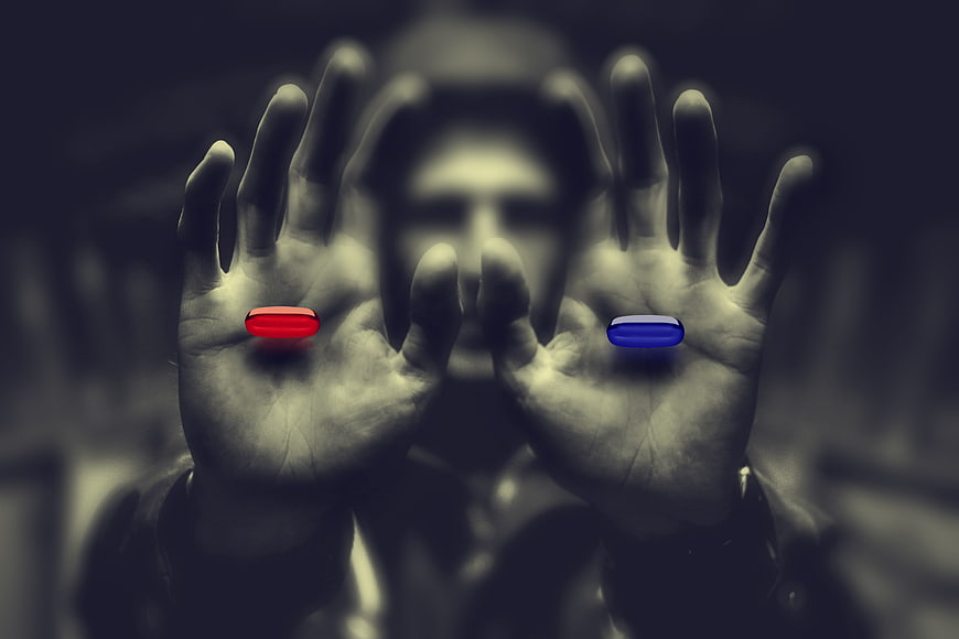 Man holding red and blue pills in hands