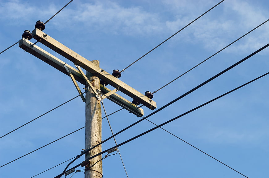 Wooden utility pole with power lines against blue sky
