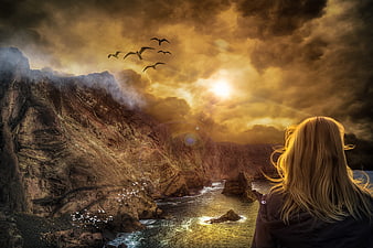 Woman Watching Dramatic Golden Sunset Over Rocky Coastline