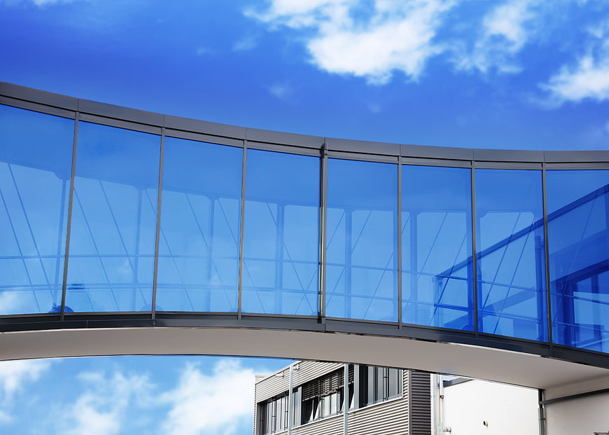 Modern Glass Skybridge Architecture Against Blue Sky