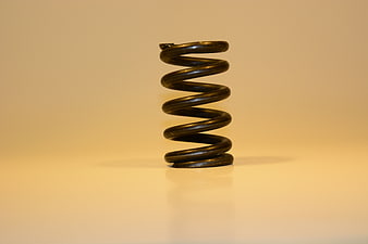 Black metal coil spring on beige background