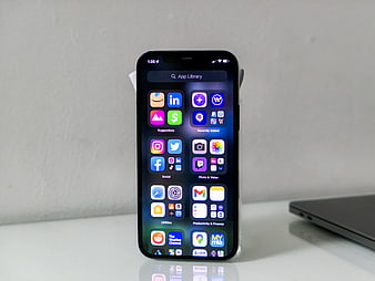 Smartphone displaying app library on white desk
