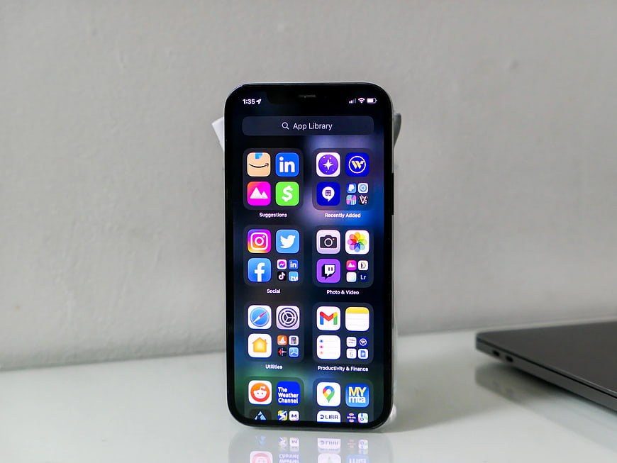 Smartphone displaying app library on white desk