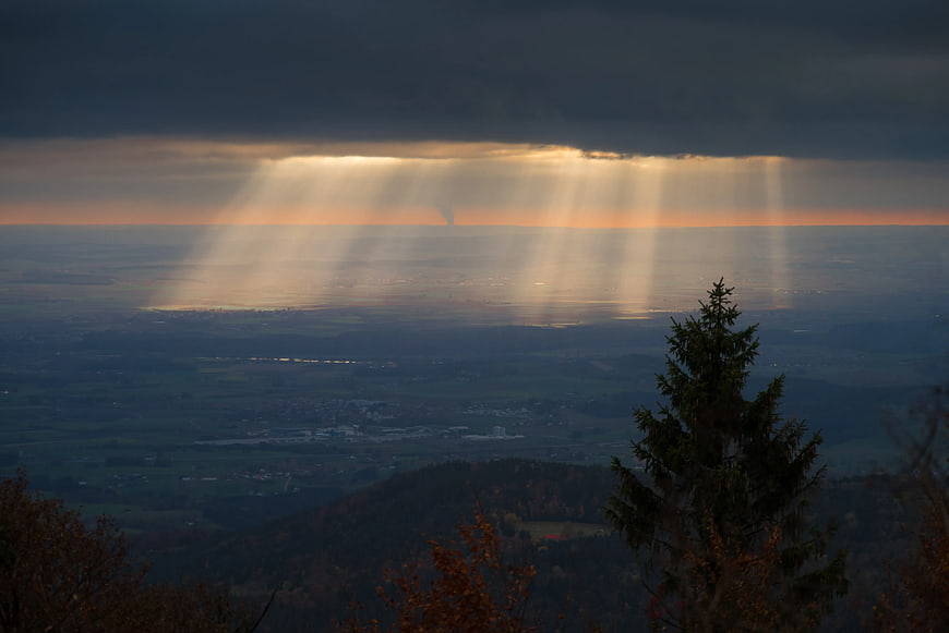 Dramatic Sunbeams Over Valley Landscape at Dusk