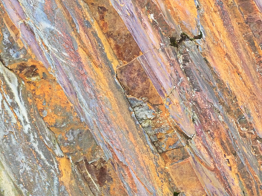 Abstract colorful rock texture with orange and purple mineral striations
