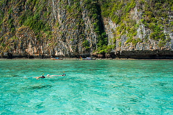 Snorkelers in Turquoise Waters Near Limestone Cliffs