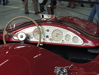 Vintage red car dashboard with chrome gauges and steering wheel