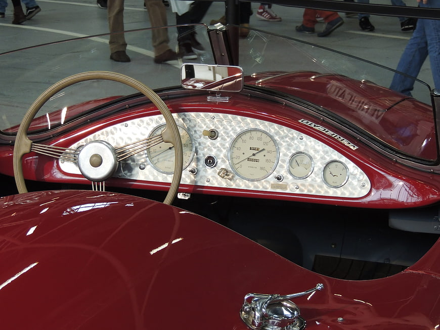 Vintage red car dashboard with chrome gauges and steering wheel