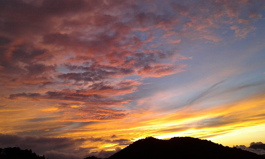 Dramatic sunset sky with colorful clouds over mountain silhouette