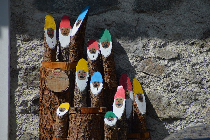 Hand-painted wooden gnome figures on rustic log display
