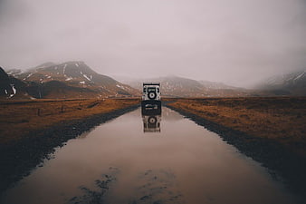 White SUV Driving on Wet Gravel Road in Mountains