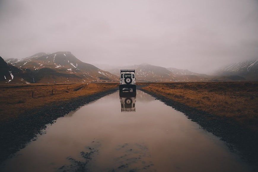 White SUV Driving on Wet Gravel Road in Mountains