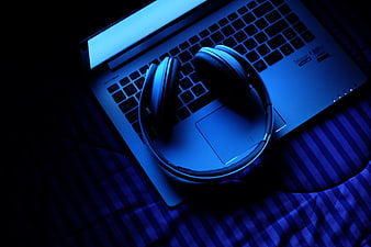 Headphones on laptop keyboard with dramatic blue lighting