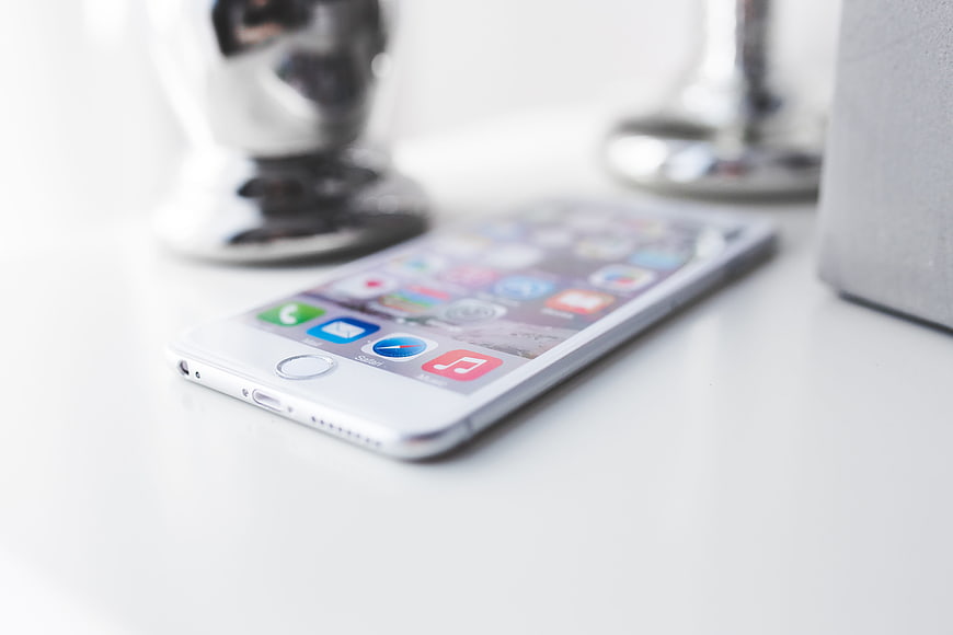 White Smartphone Lying On White Desk With Blurred Background