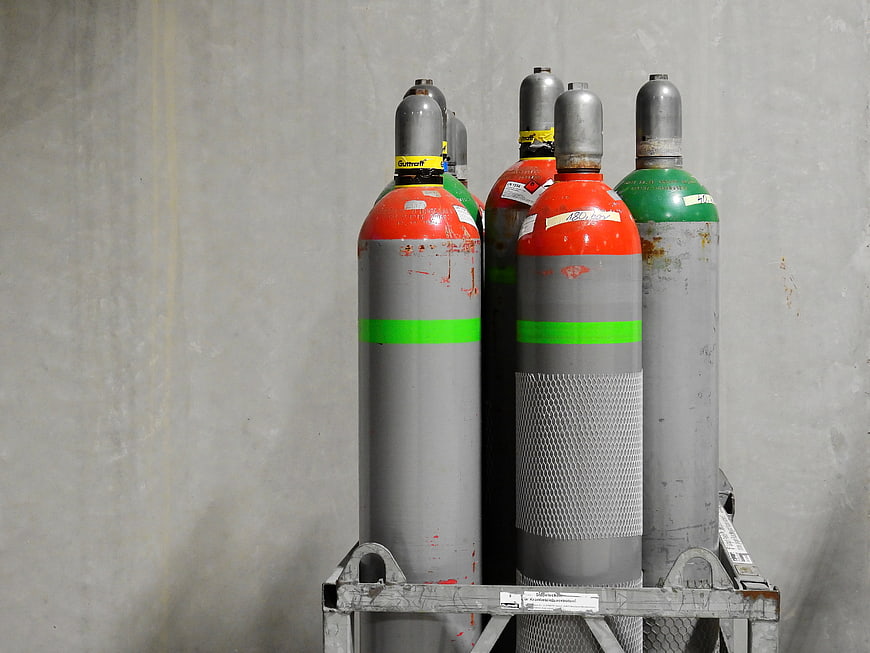 Industrial Gas Cylinders On Metal Rack Against Concrete Wall