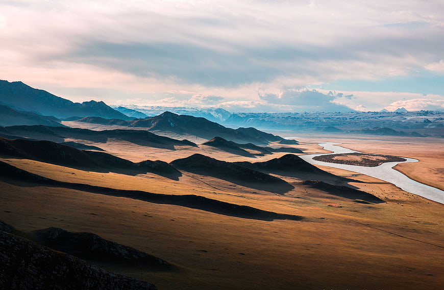 Scenic River Valley with Rolling Hills and Distant Mountains