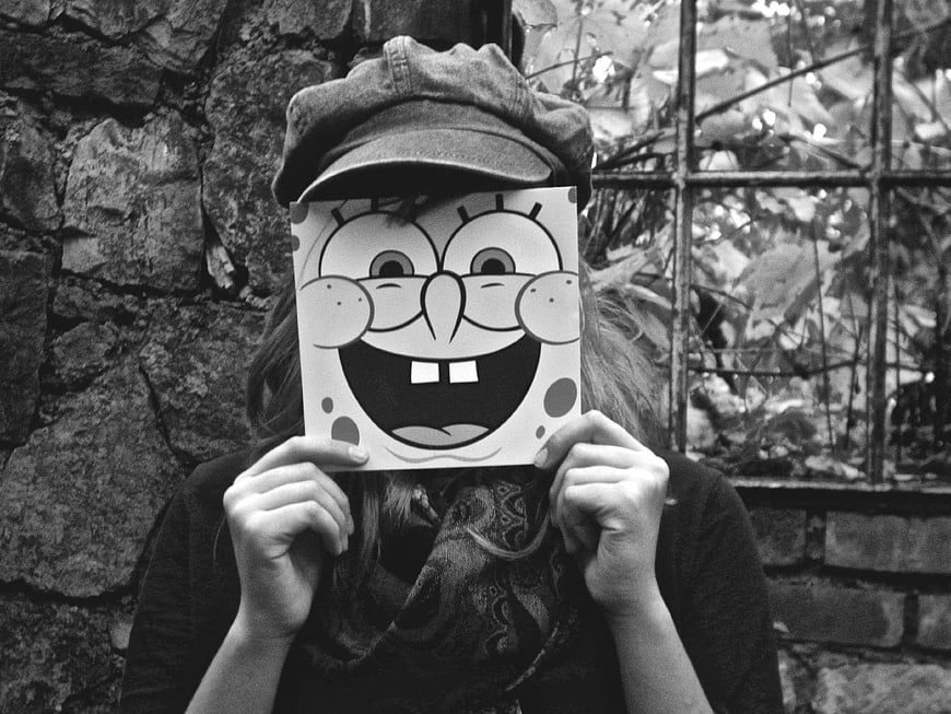 Girl holding SpongeBob cutout mask in black and white