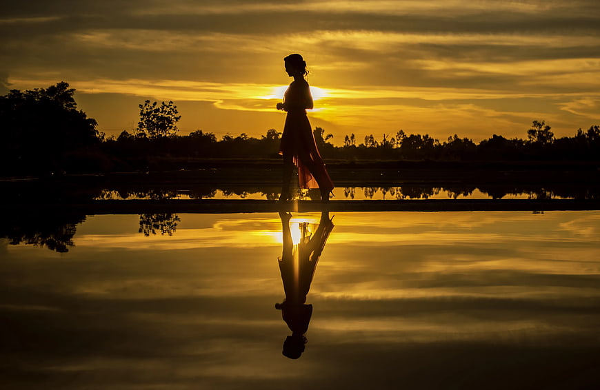 Silhouette of Woman Walking on Bridge at Golden Sunset