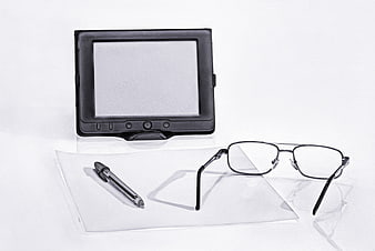 E-reader, glasses, and pen on white paper for digital reading concept