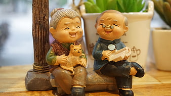 Smiling elderly couple figurines with cat on wooden bench