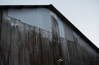 Weathered corrugated metal barn wall with single light fixture