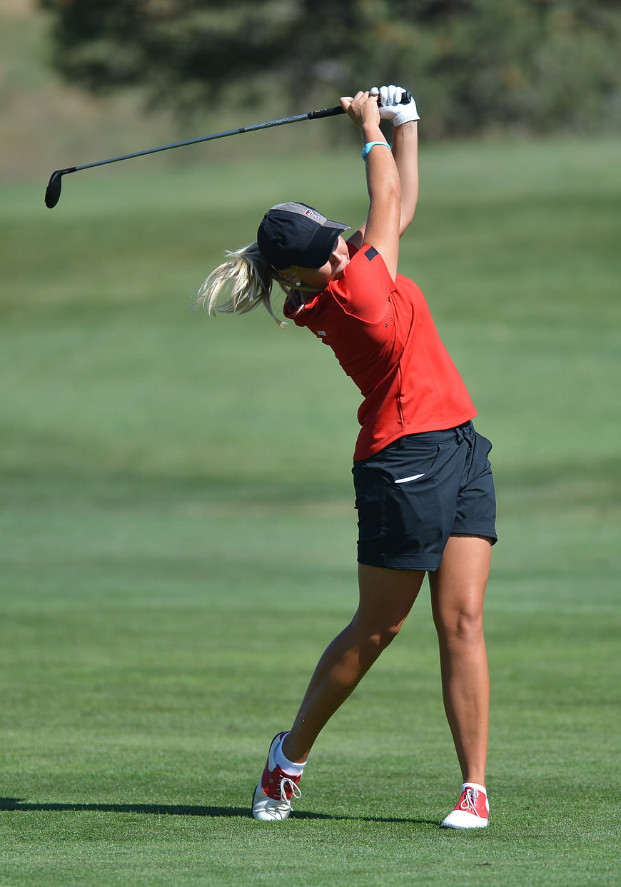 Female Golfer Swinging Club on Green Course
