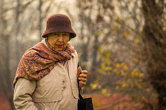 Senior woman in beige coat and patterned scarf in autumn park
