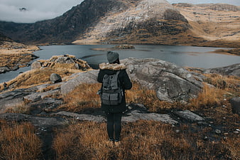 Hiker with Backpack Overlooking Mountain Lake in Highlands