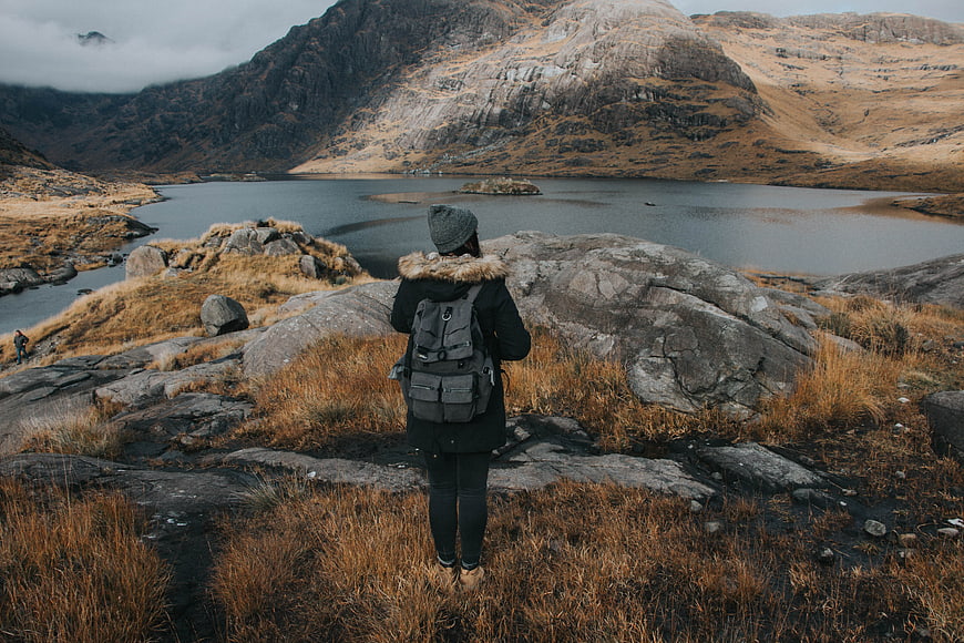 Hiker with Backpack Overlooking Mountain Lake in Highlands
