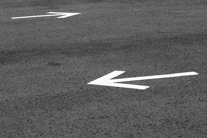 Black and white road arrows pointing in opposite directions on asphalt