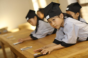 Young Students in Traditional Chinese Medicine Attire at Wooden Table