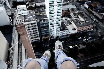 First-person view of legs dangling over a high-rise city edge