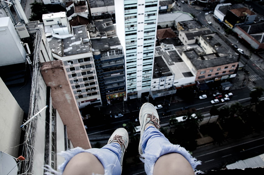 First-person view of legs dangling over a high-rise city edge