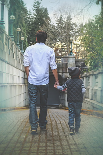 Father and son walking hand in hand on a cobblestone path