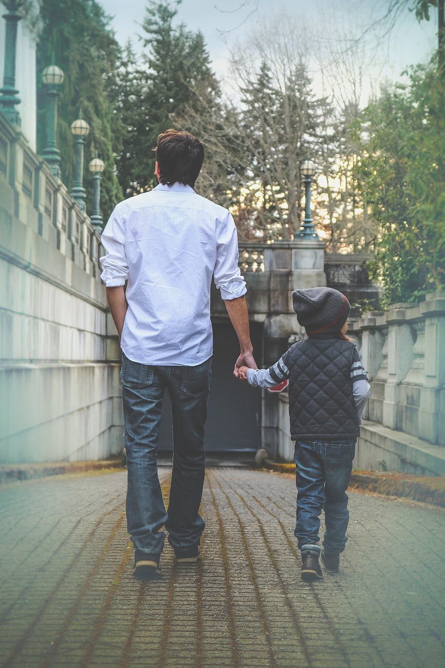 Father and son walking hand in hand on a cobblestone path