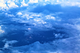 Aerial View of Snow-Capped Mountains Through Blue Clouds