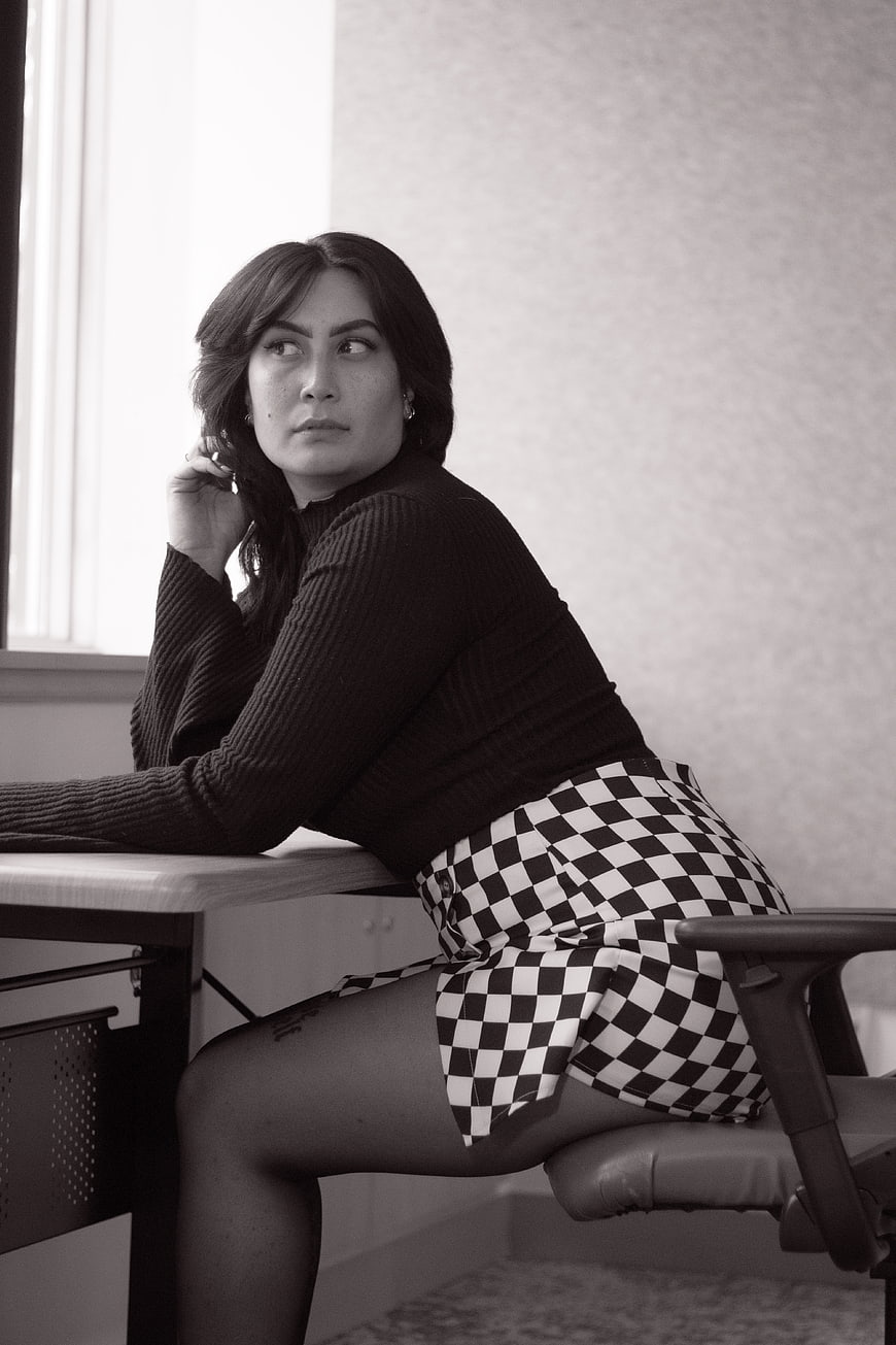 Woman in Checkered Skirt Sitting at Desk in Black and White