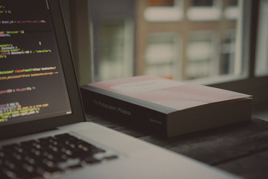 Laptop with code and photography book on desk