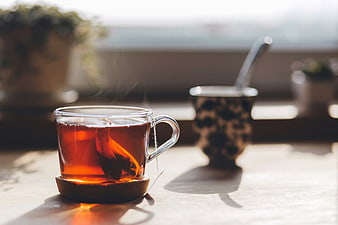 Steaming glass cup of hot tea on wooden table