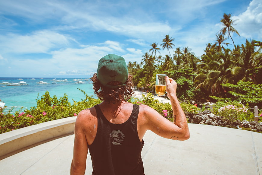 Man with beer overlooking tropical ocean resort