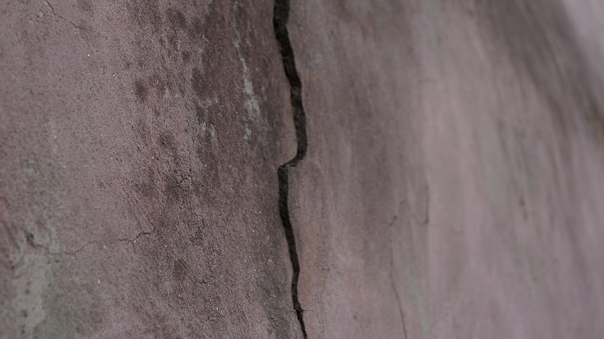 Close-up of cracked concrete wall texture with peeling paint