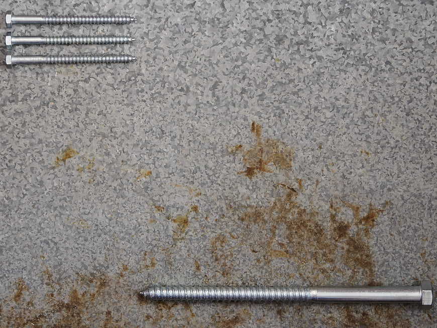 Metal screws on rusty industrial metal plate background