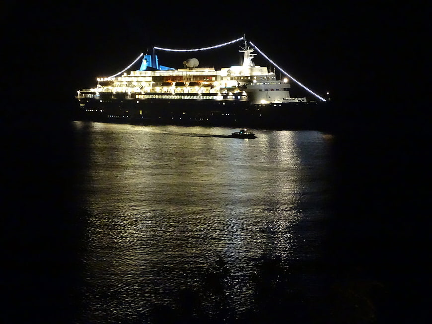Illuminated cruise ship sailing on dark ocean at night