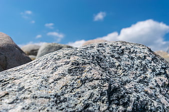Close-up of textured granite rock against blue sky