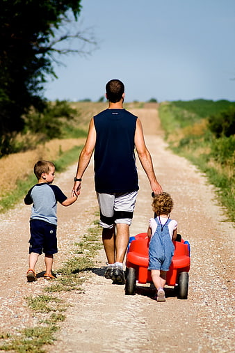 Father Walking With Two Children On Dirt Road
