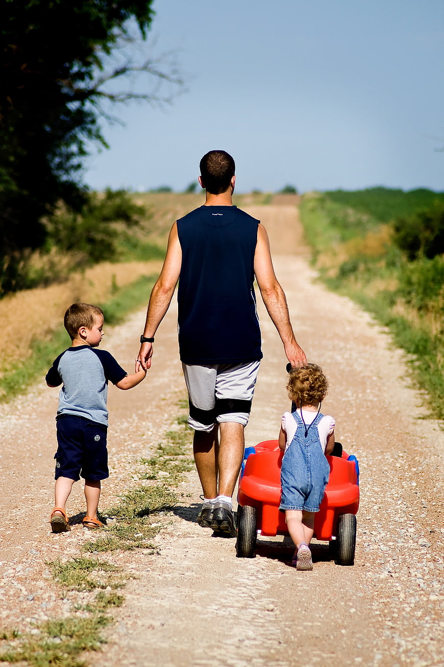 Father Walking With Two Children On Dirt Road