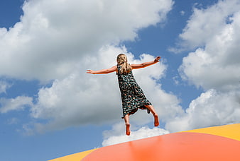 Girl Jumping on Trampoline Against Blue Sky