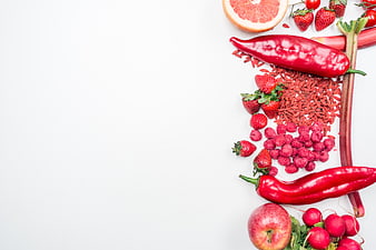 Flat lay of red fruits and vegetables on white background