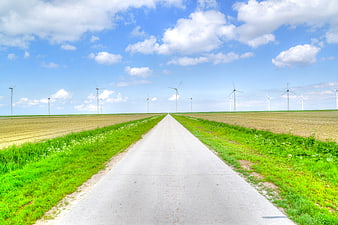 Straight Road Leading to Wind Turbines in Green Fields